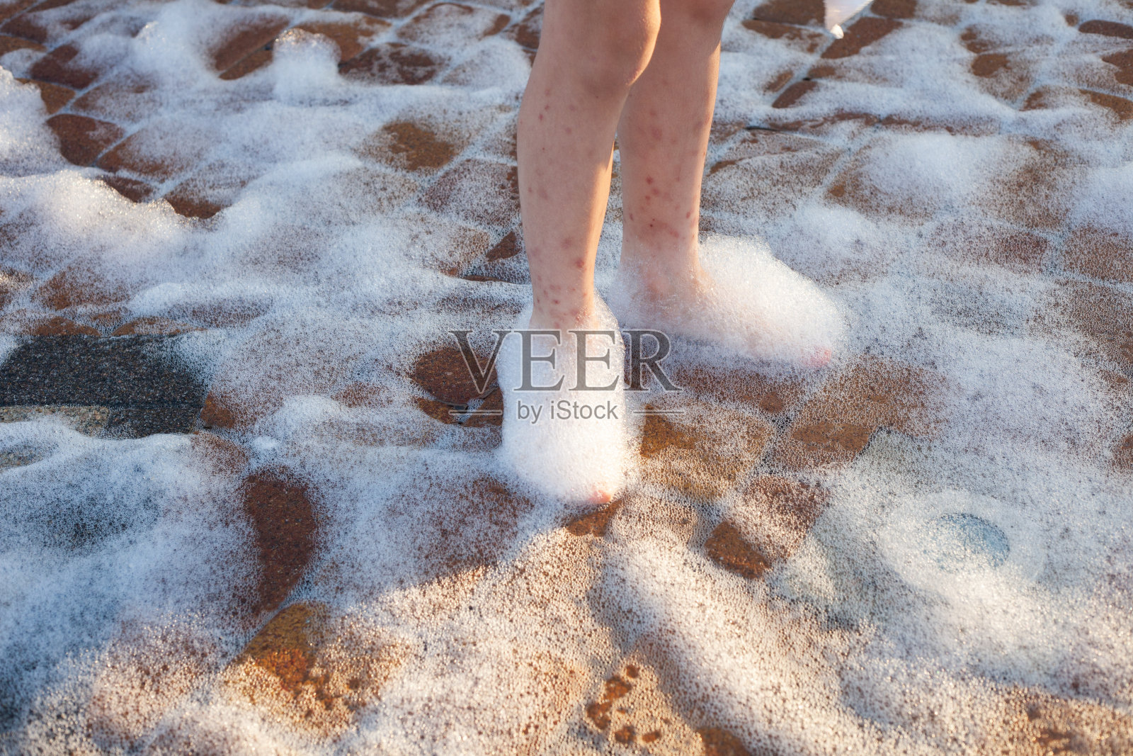 孩子的脚上有肥皂泡沫上的咬痕照片摄影图片