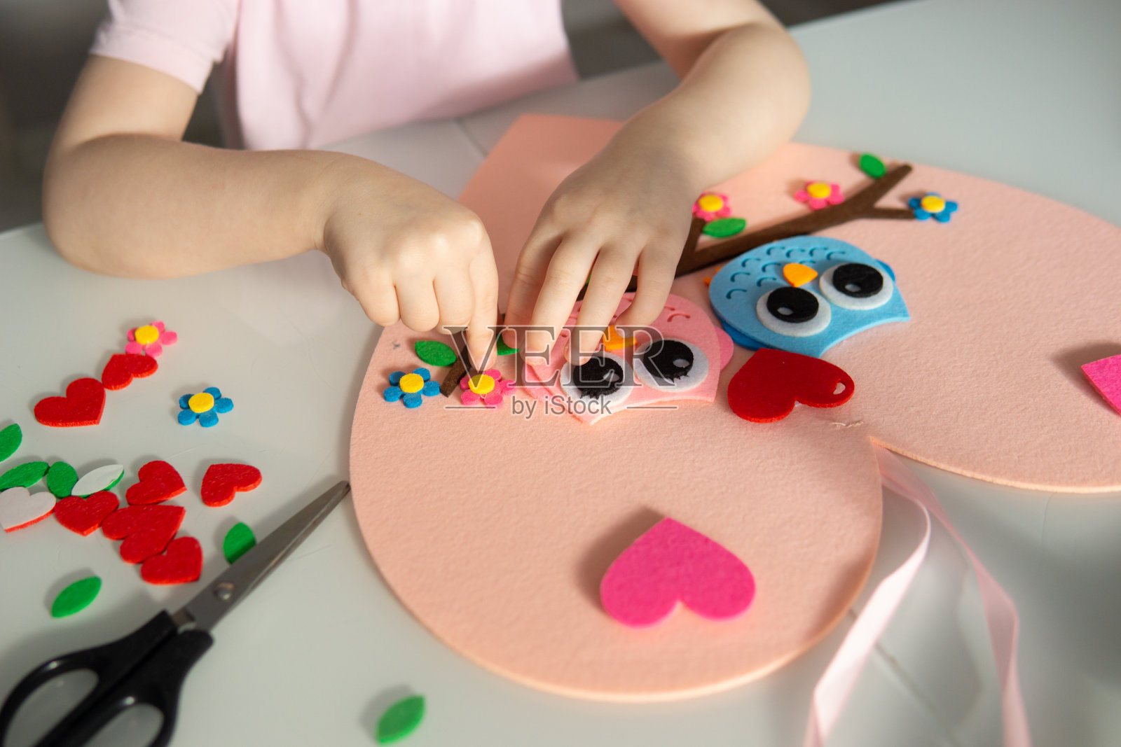 一个博主女孩为情人节制作了一个心形的毡工艺品。儿童创意和手工的概念。照片摄影图片