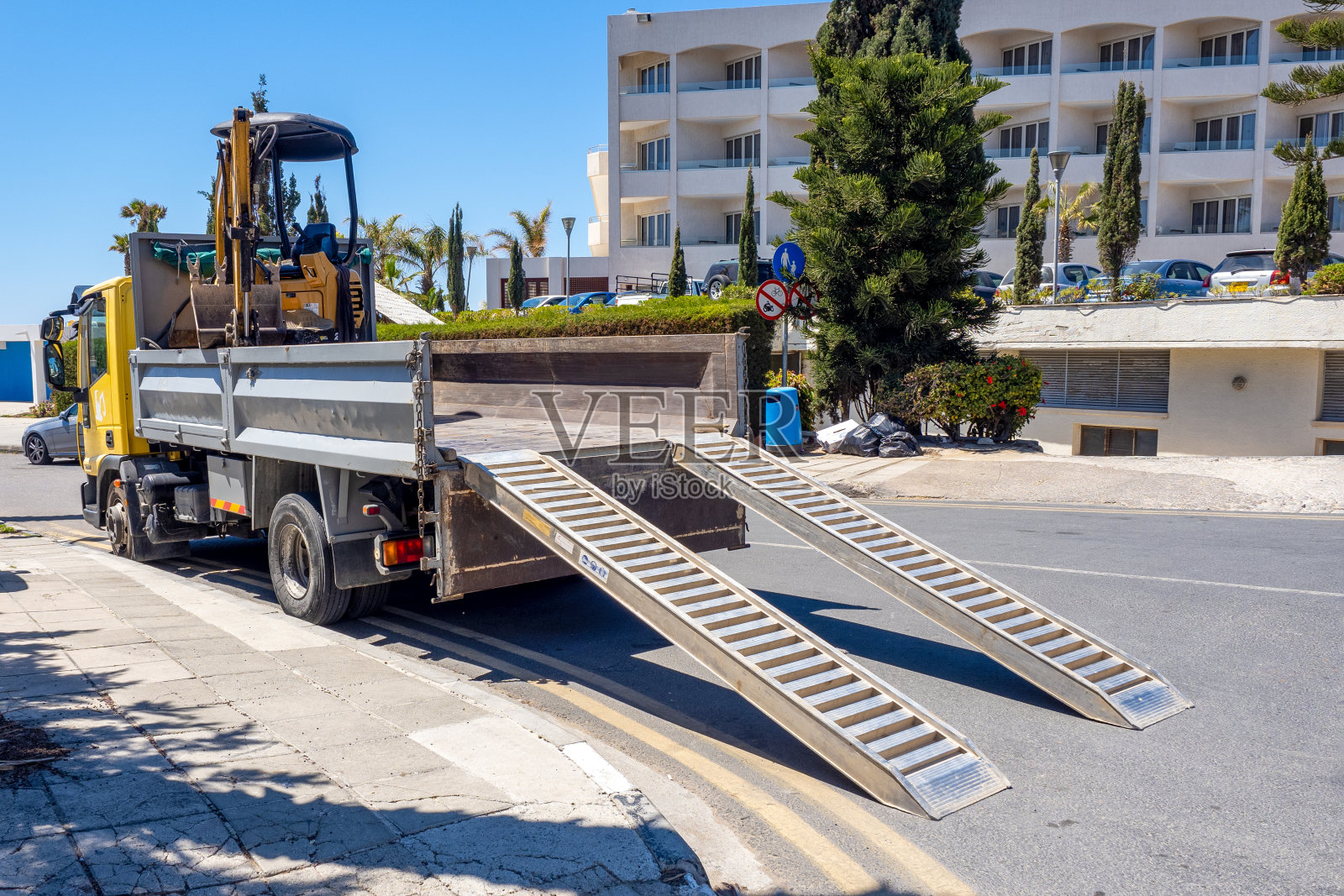 卡车带来了一台小型挖掘机进行维修。将挖掘机装到卡车上照片摄影图片