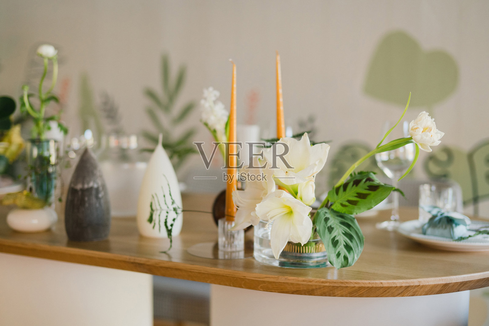 婚宴的餐桌布置。有美丽的花朵和绿色植物的花卉作品，蜡烛，装饰好的桌子上的摆设和盘子。照片摄影图片