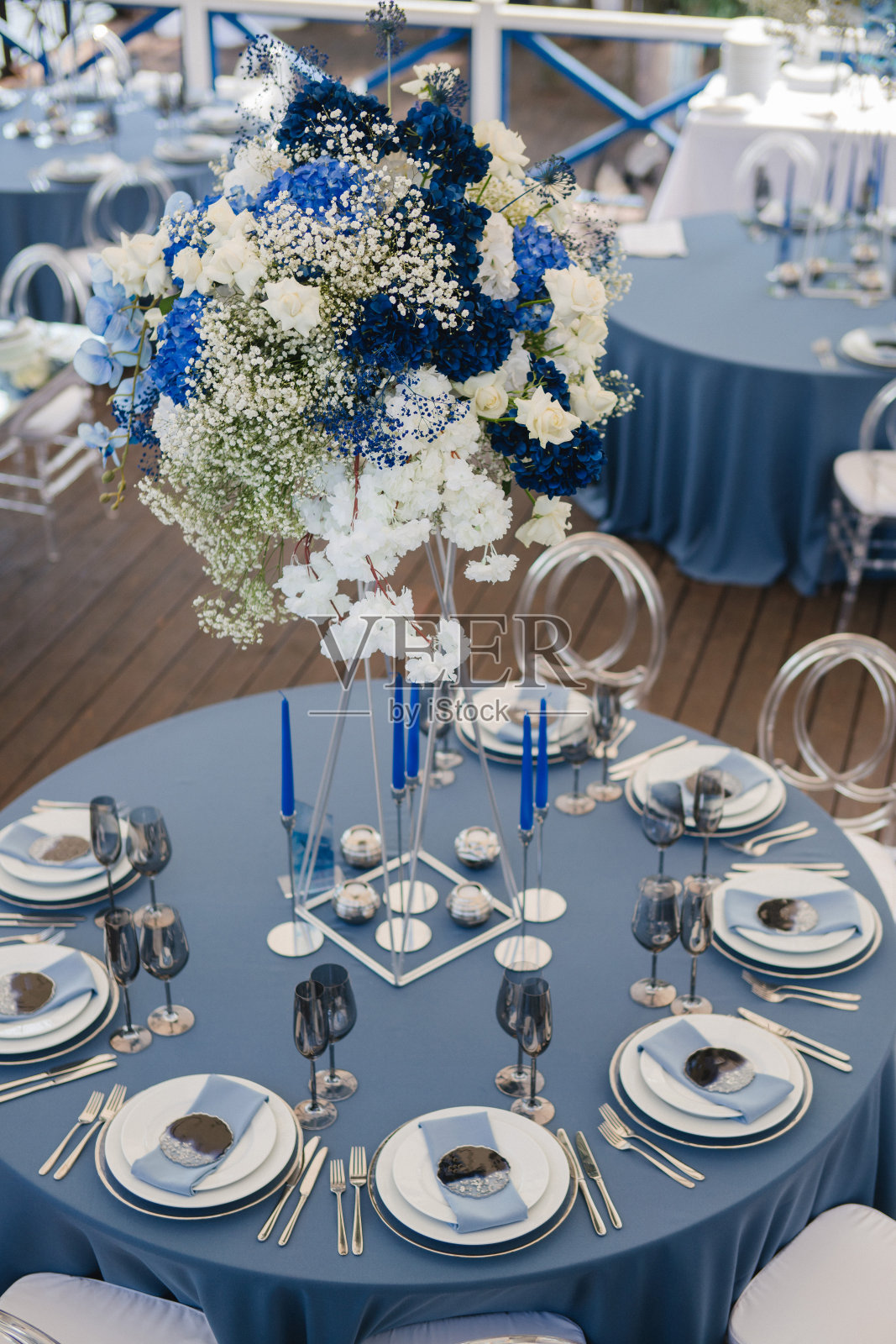 婚宴的餐桌布置。有美丽的花朵和绿色植物的花卉作品，蜡烛，装饰好的桌子上的摆设和盘子。照片摄影图片