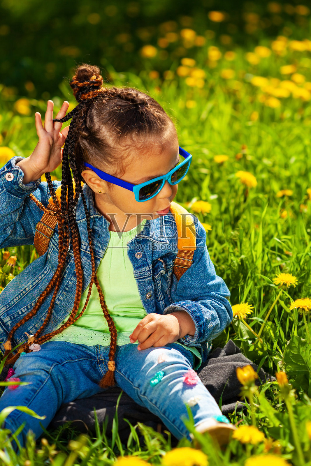 时髦的女婴戴着太阳镜坐在大自然的草地上照片摄影图片