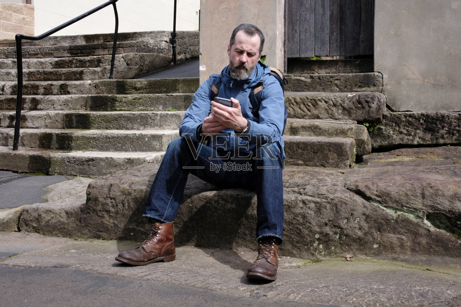 一个男人在看他的智能手机。照片摄影图片