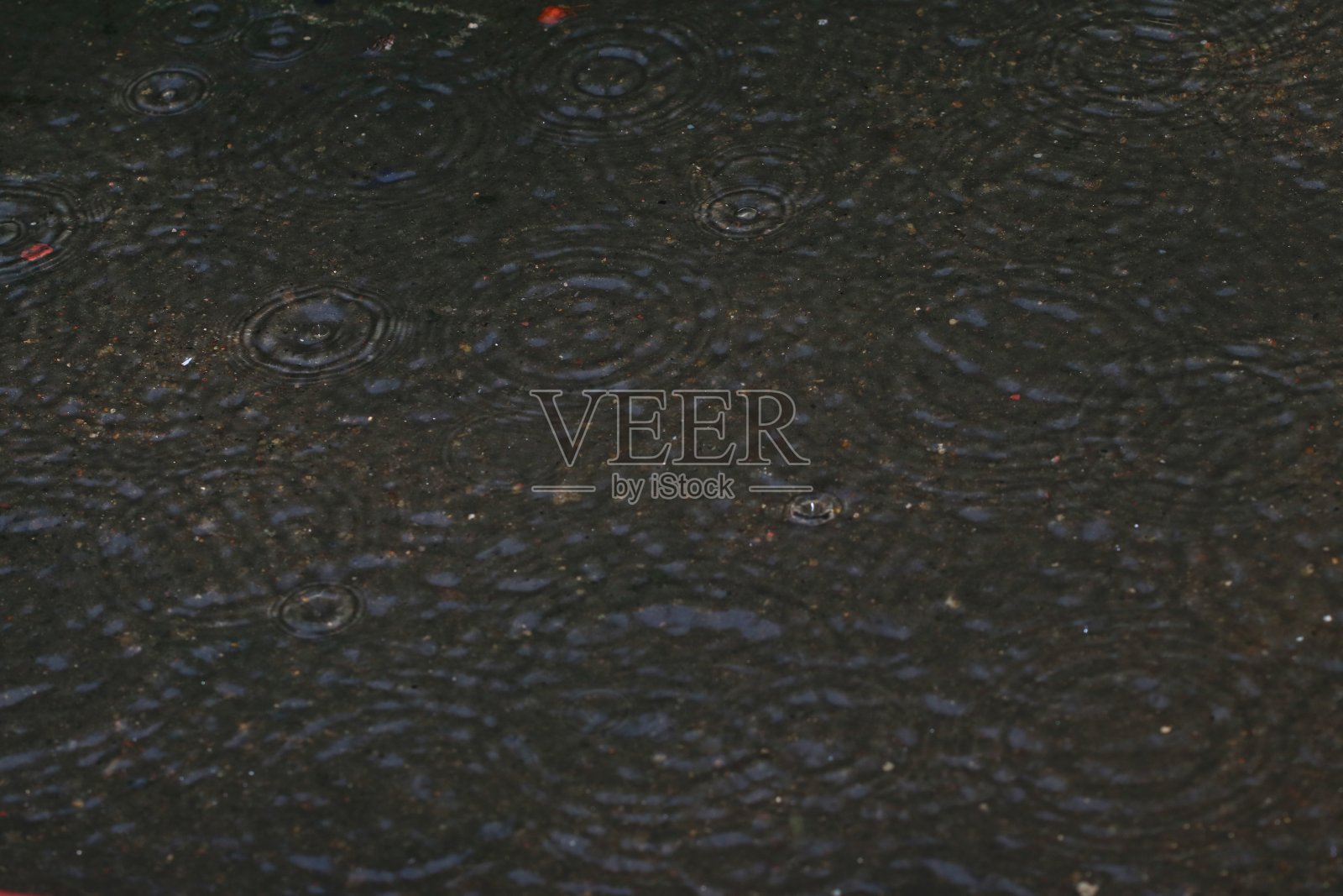 下雨时，水溅在地板上形成圆形图案。照片摄影图片