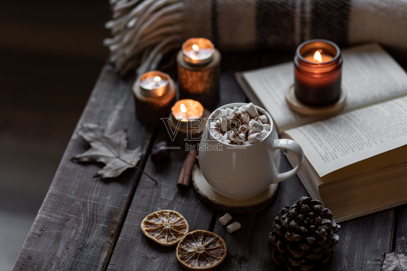 秋天舒适的家庭组成与热巧克力，棉花糖和蜡烛。在一个灰色的秋天的早晨，芳香疗法，舒适和放松的气氛。木制背景，书籍，特写。照片摄影图片