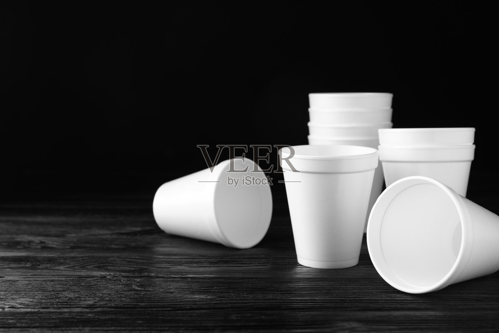 黑色木桌上有许多白色泡沫塑料杯子，有空间放文字照片摄影图片