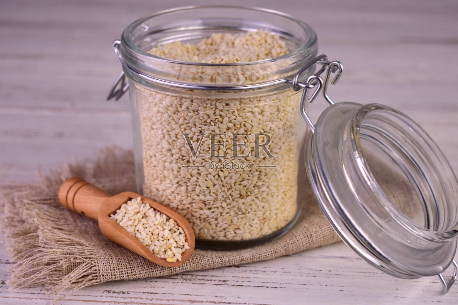 白芝麻放在一个罐子里，背景是木制的。特写。照片摄影图片