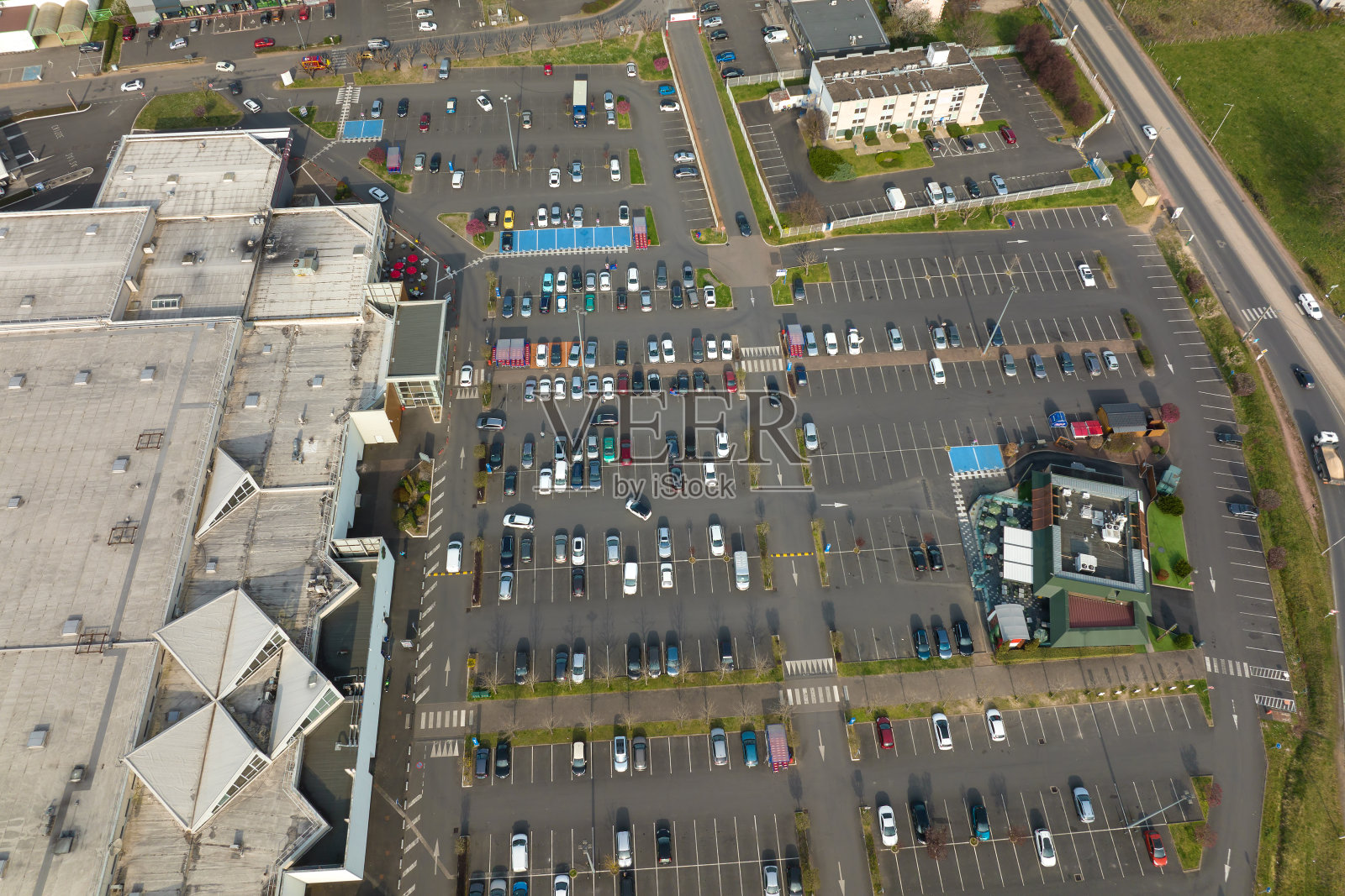 许多五颜六色的汽车停在停车场上的鸟瞰图，上面有停车地点和方向的线条和标记照片摄影图片