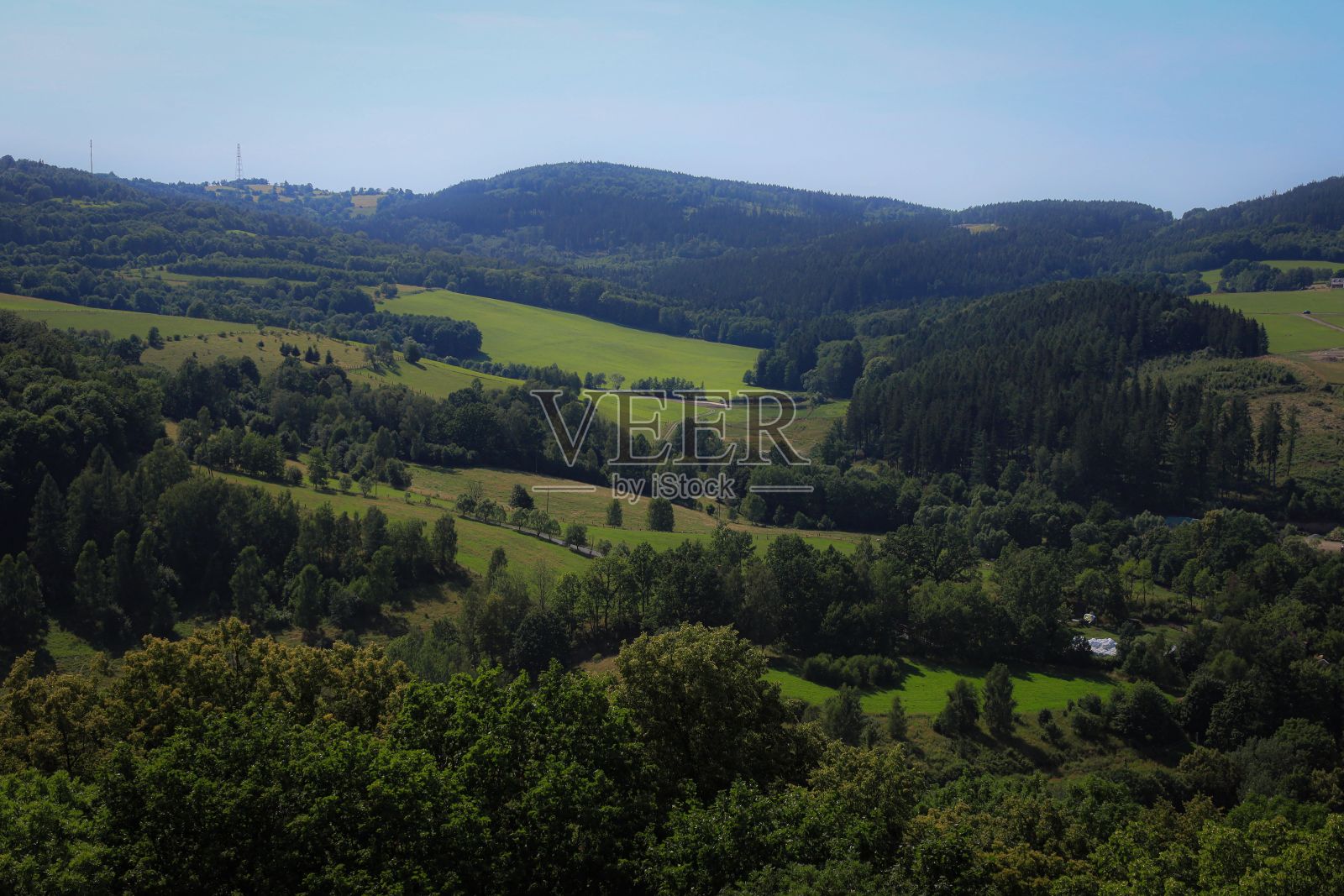空中拍摄的田野，郁郁葱葱的绿色树木，在一个晴朗的日子里，蓝天照片摄影图片