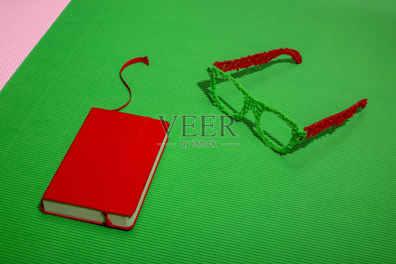 红色笔记本，绿色背景，彩色眼镜照片摄影图片