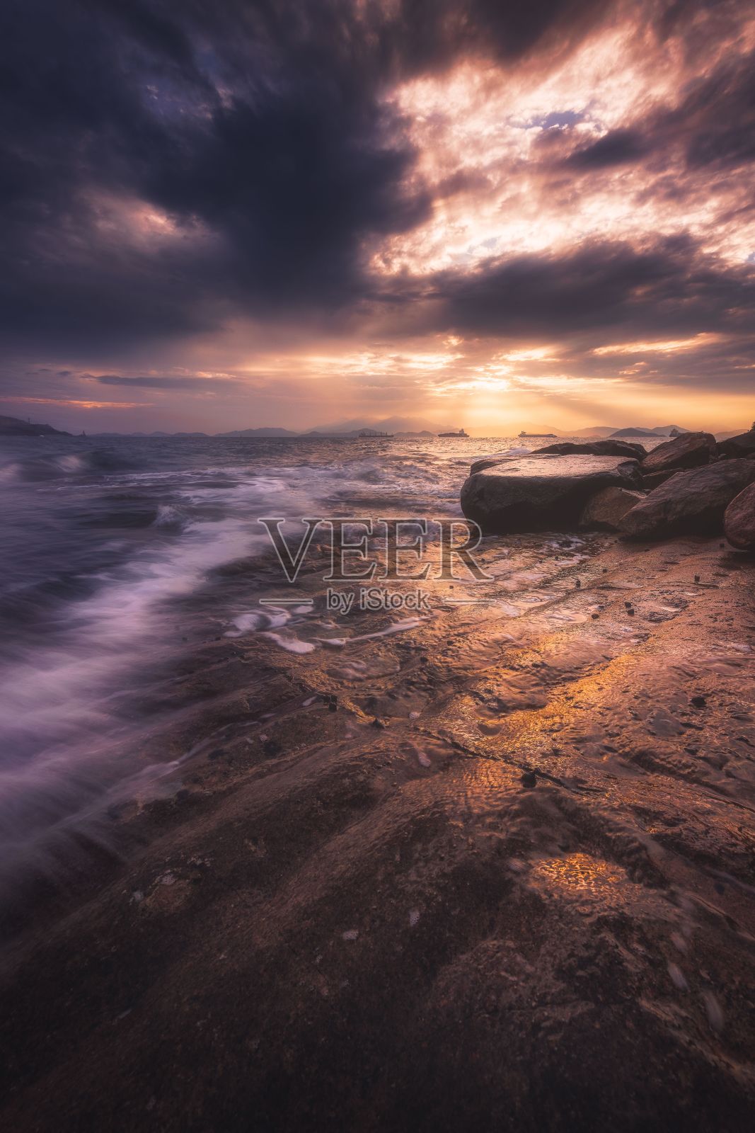 垂直拍摄的海浪在日落时撞击海滩的悬崖照片摄影图片