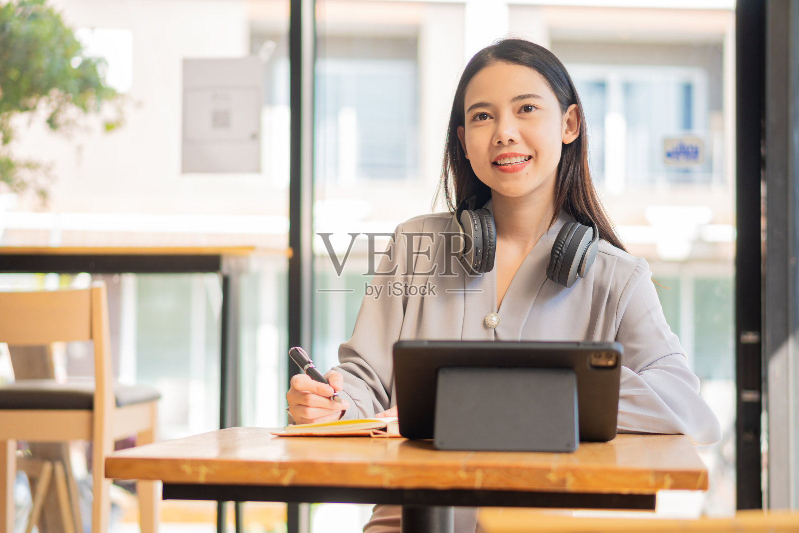 一名大学生坐在咖啡店里，戴着耳机用平板电脑工作照片摄影图片