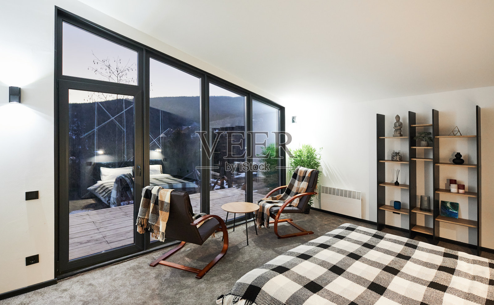 时尚，家具齐全的卧室，不规则的全景窗在黄昏。照片摄影图片