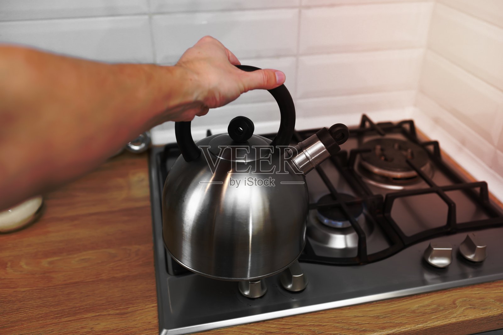 男人手拿金属水壶在厨房里。水壶用热水烧开茶、咖啡、奶粉等饮料。照片摄影图片