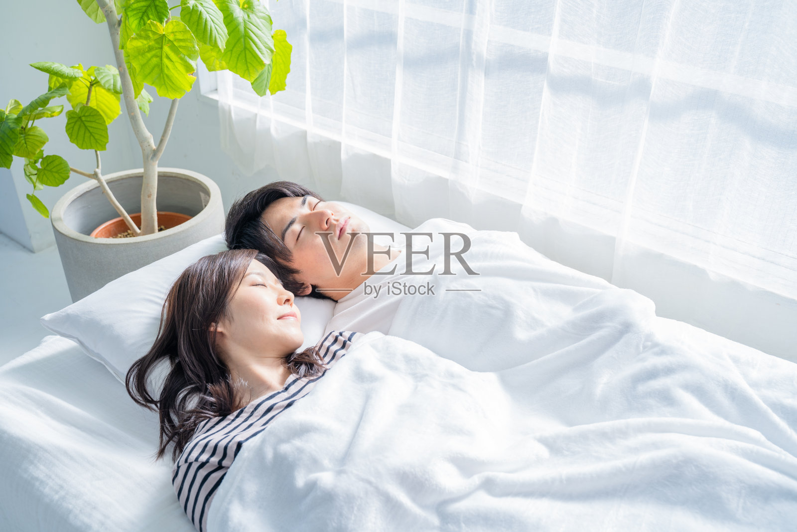 一对年轻夫妇睡在卧室的床上。照片摄影图片