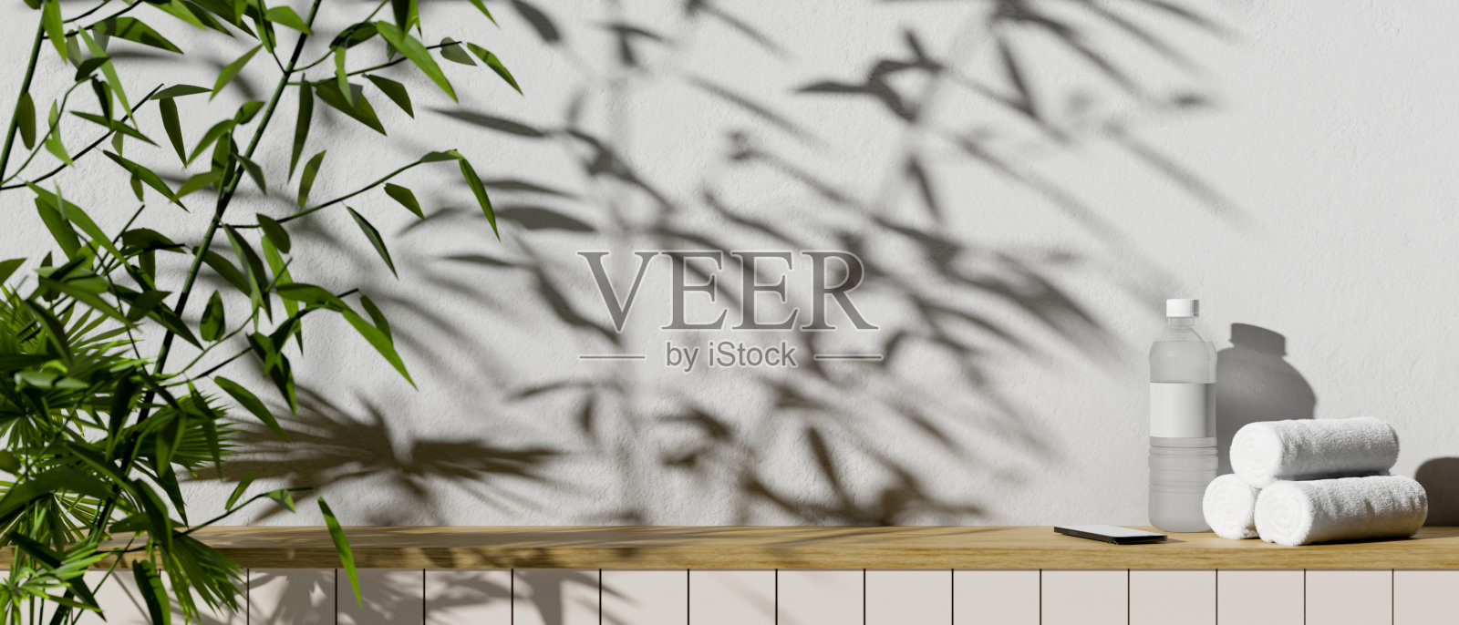 一瓶水、毛巾、智能手机和复印空间放在一张靠白墙的小木桌上照片摄影图片