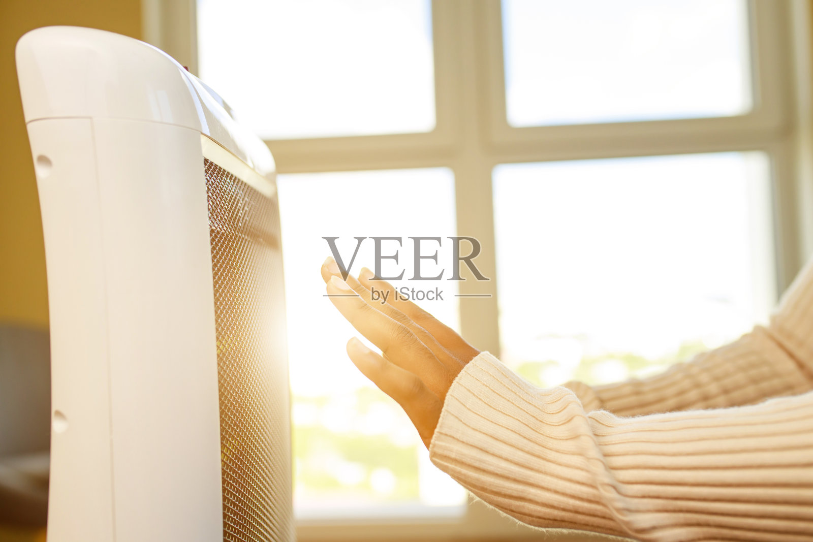 拉丁美洲妇女在寒冷的房间里用加热器暖手照片摄影图片