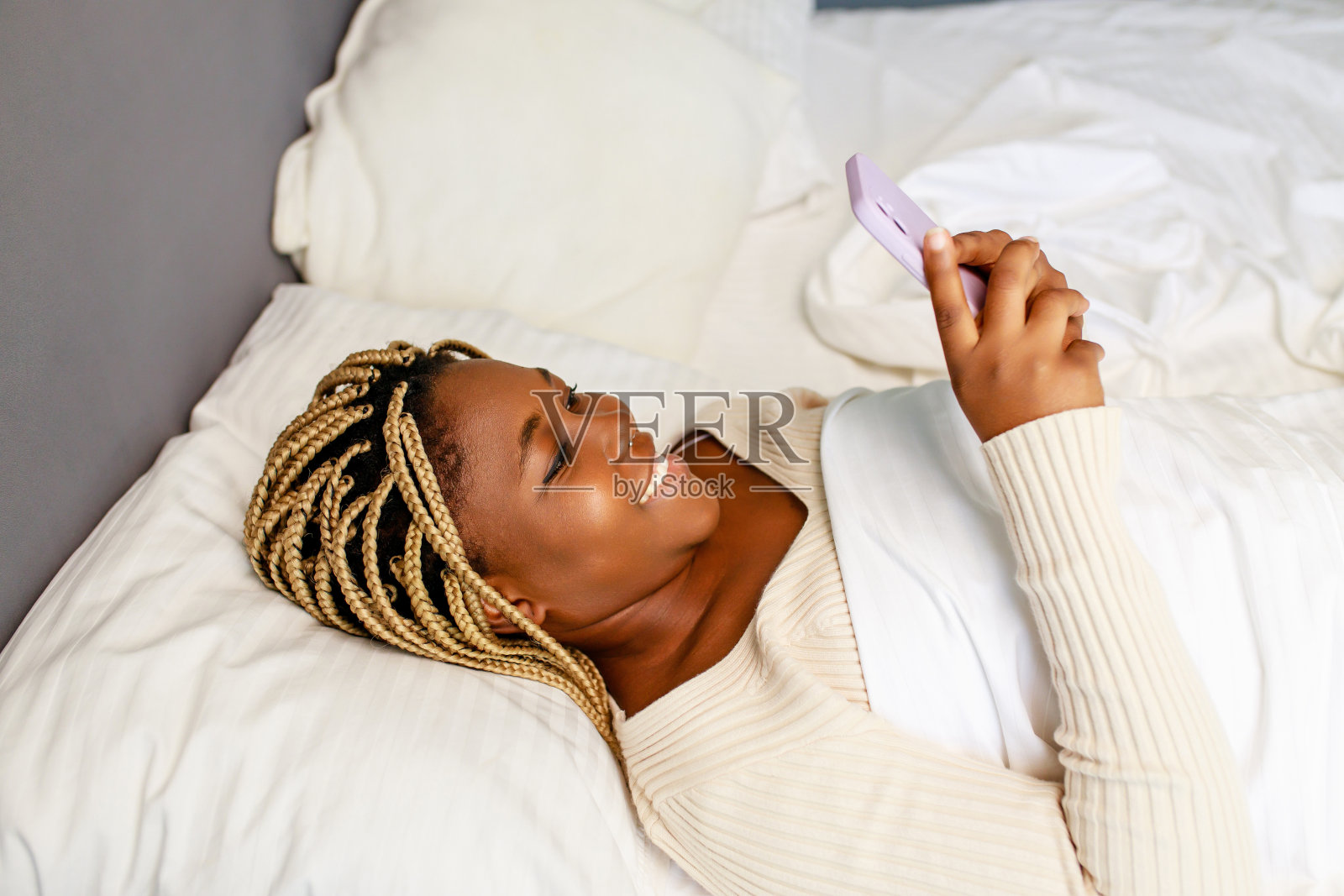 一名拉丁美洲妇女在床上醒来后打电话照片摄影图片