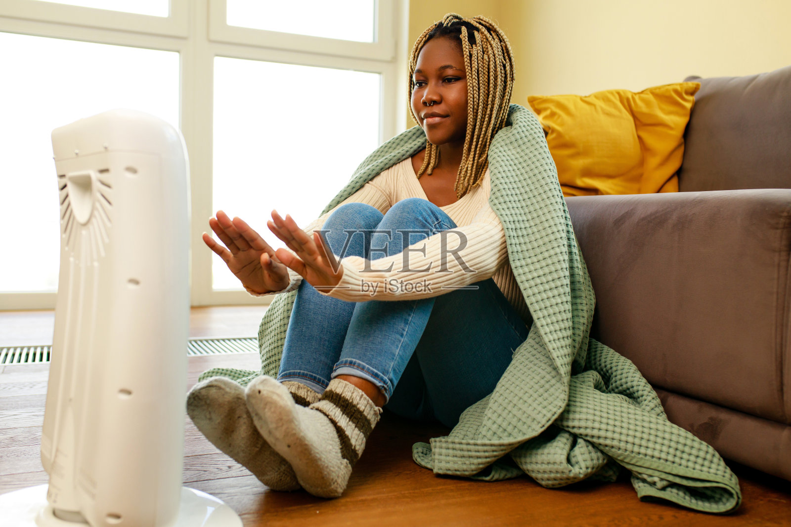 非裔美国妇女在蓝色毯子温暖附近的电加热器在家里照片摄影图片