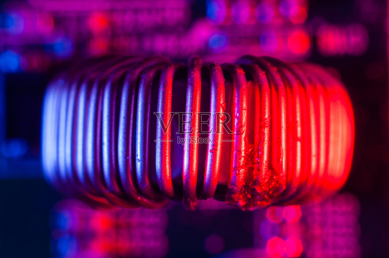 在红色和蓝色照明下，电子PCB上的单铜感应线圈与铜线紧密相连照片摄影图片