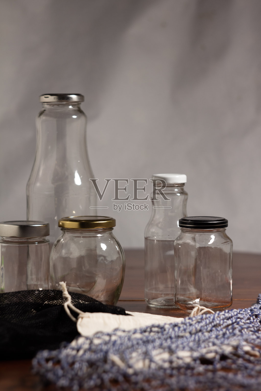 可重复使用的容器——布袋和玻璃瓶，可重复使用，放在深色木桌上，有浅色背景照片摄影图片