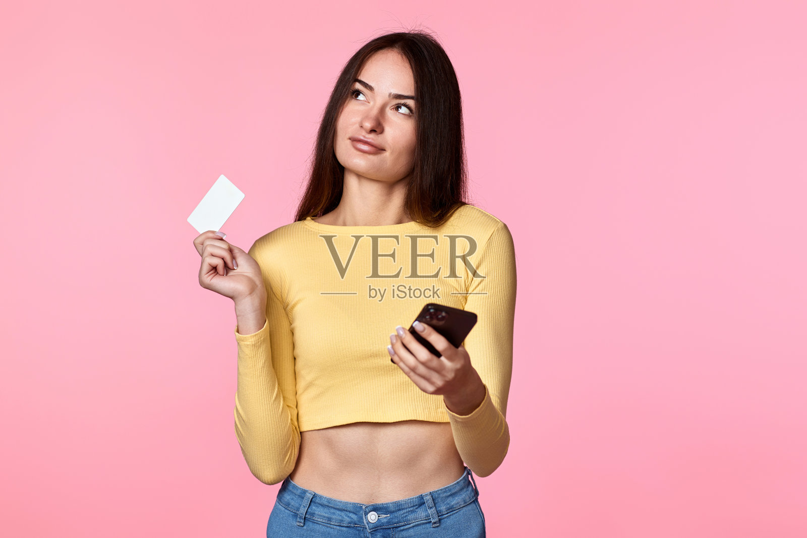 身穿黄色衣服的女子手持塑料信用卡照片摄影图片