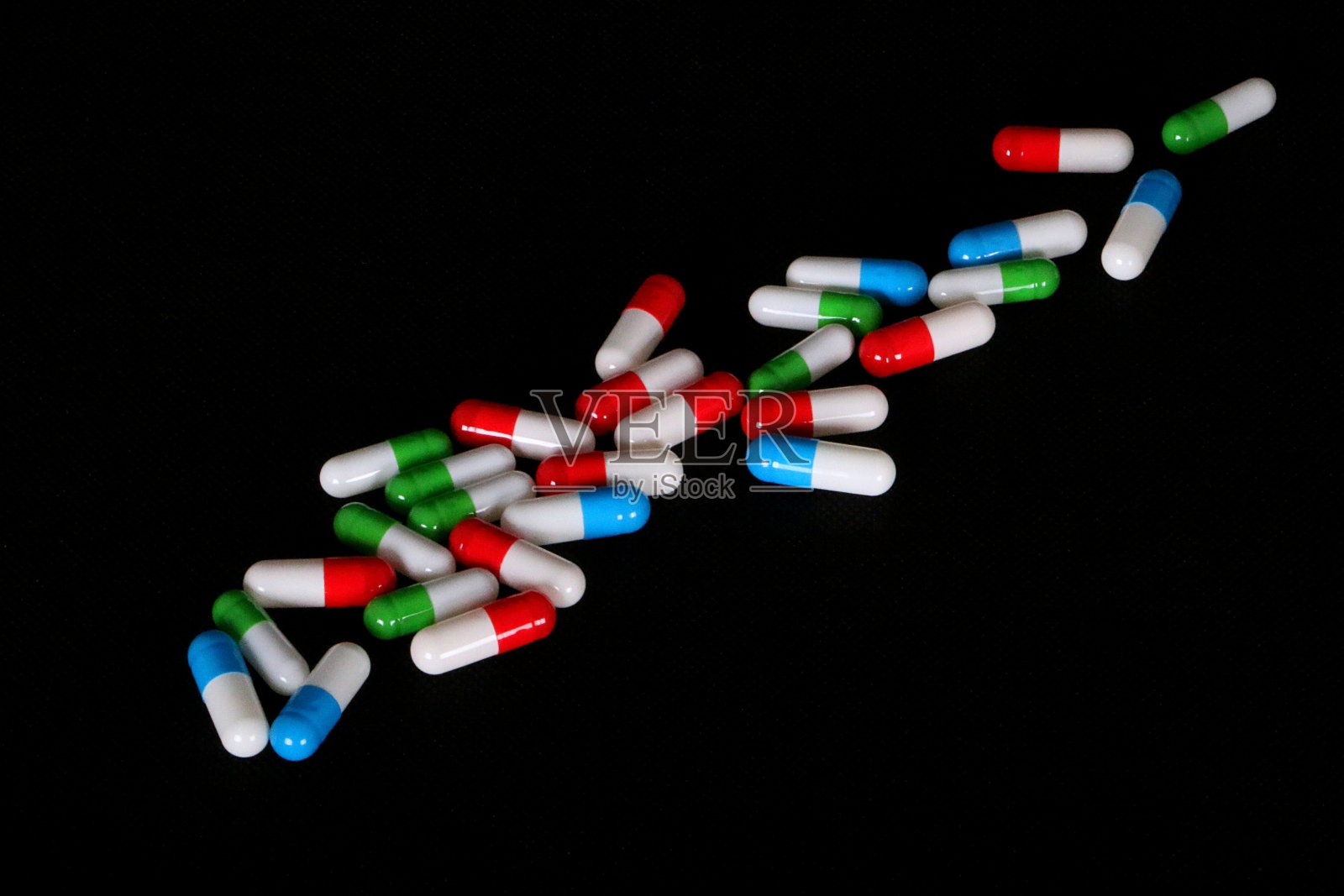 黑色的地上躺着一堆难解的彩色胶囊照片摄影图片