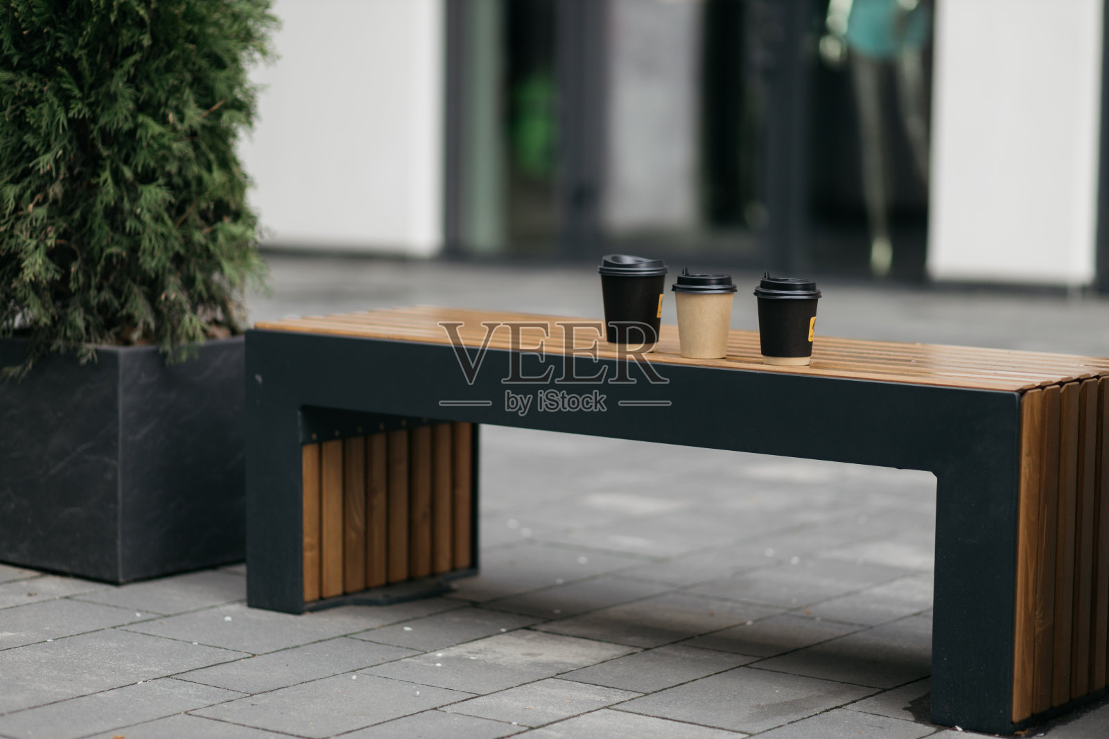 有盖的咖啡纸杯放在公园的长椅上。夏日，阳光和闪光。暖色调。照片摄影图片