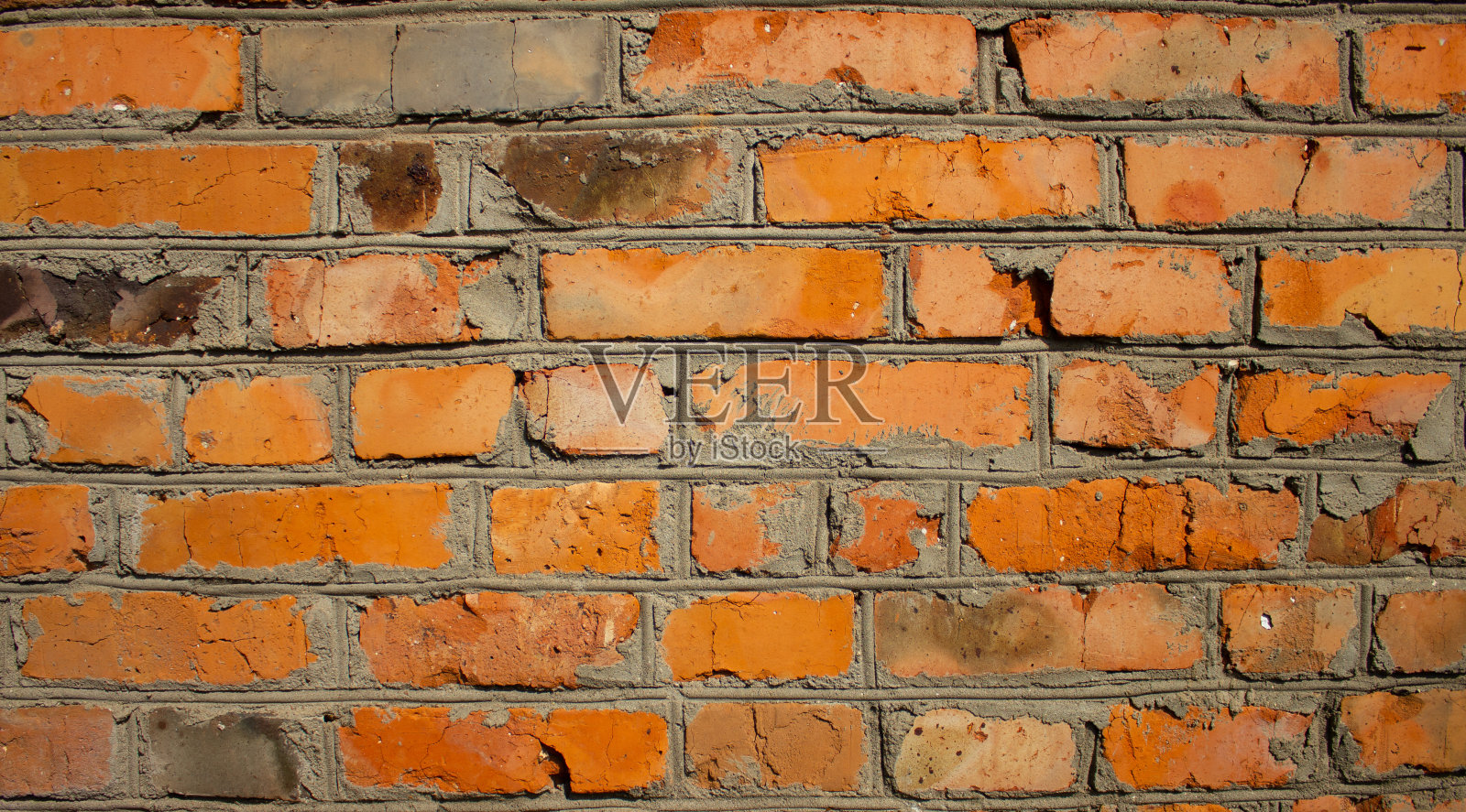 背景是由红砖和水泥制成的旧砖墙。墙体因暴露于大气现象而开裂。这块砖有些地方裂开了。照片摄影图片