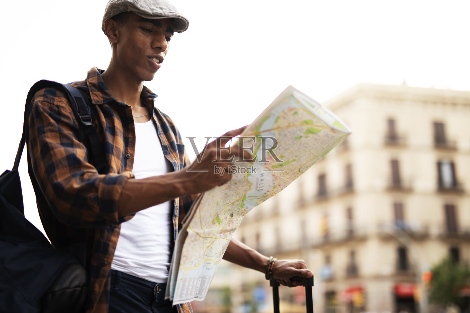 年轻英俊的男性旅行者，站在街上看着地图照片摄影图片