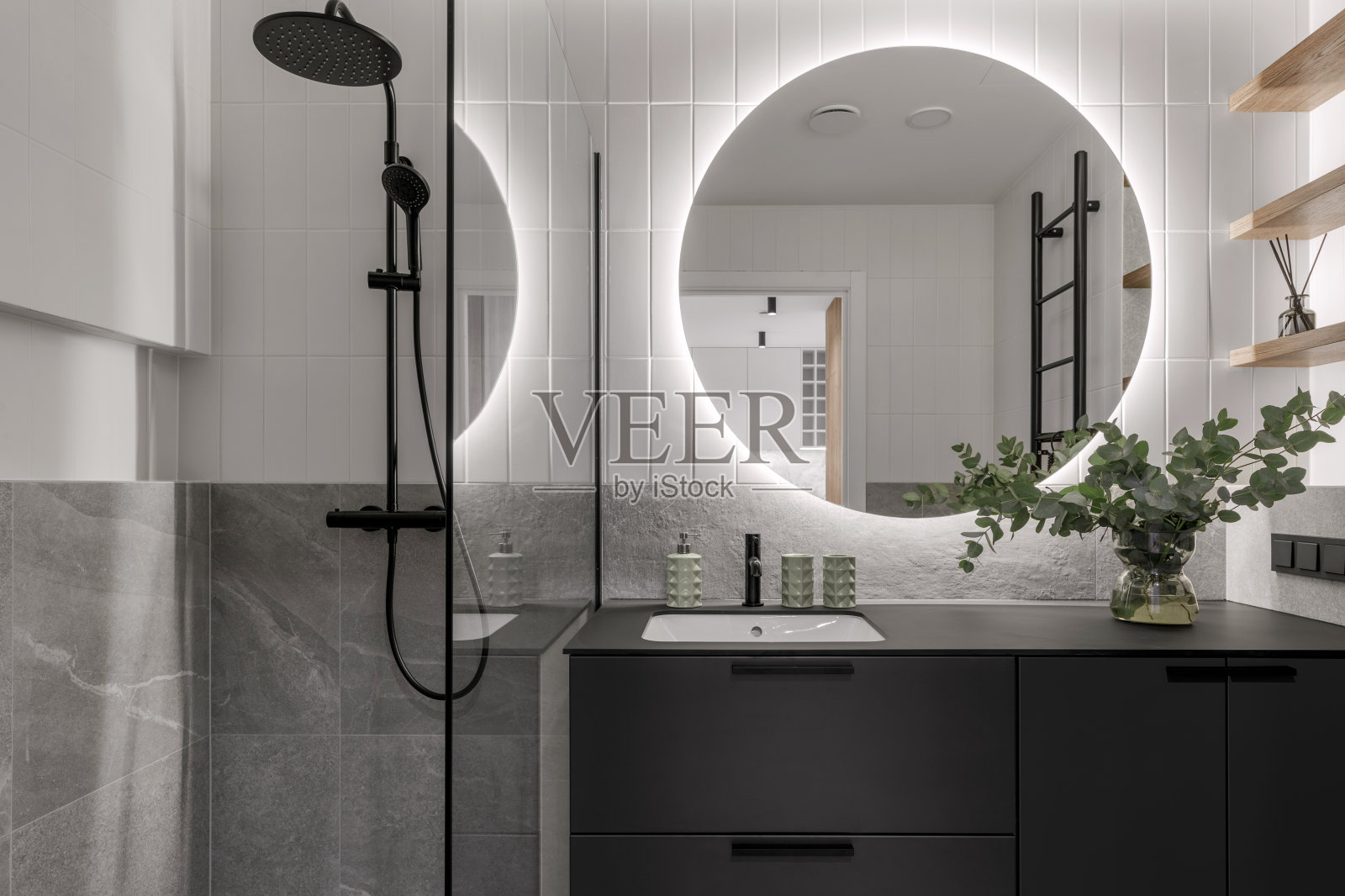 现代简约的浴室室内设计，灰色石材瓷砖，黑色家具，桉树玻璃花瓶，圆形镜子。唯美简洁的室内设计理念。照片摄影图片