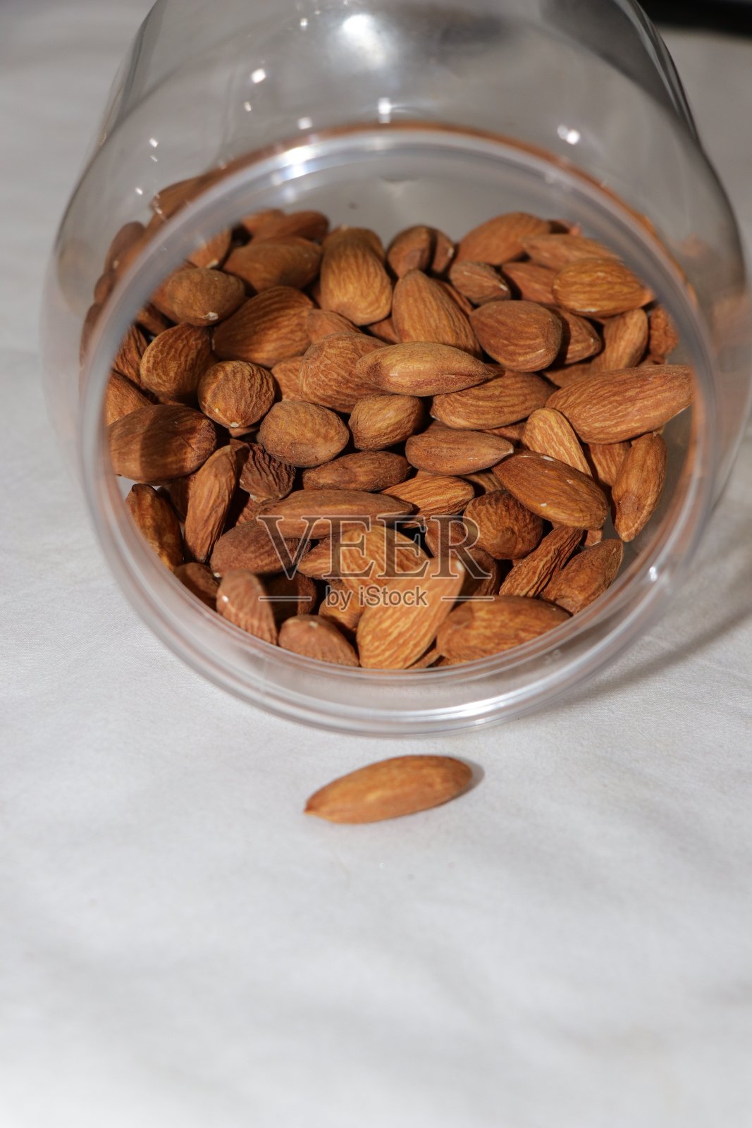 新鲜杏仁装入玻璃罐中，白色背景，有机杏仁装入罐中。白色背景上隔离的一组螺母。照片摄影图片