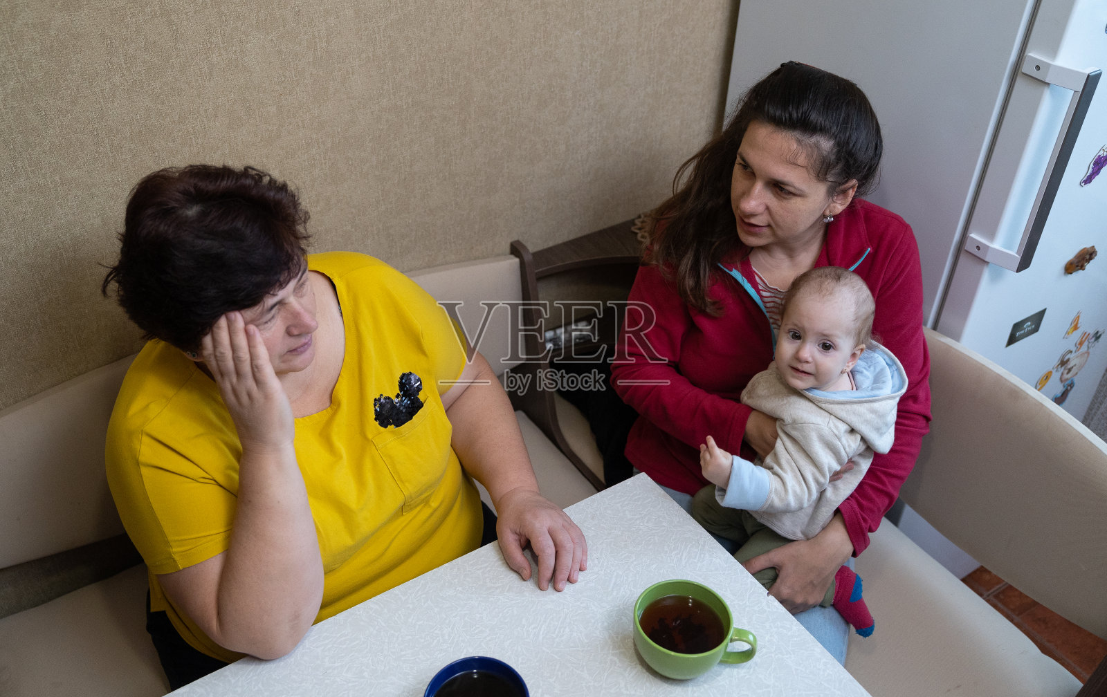 这名女子在和家人喝茶时头痛。照片摄影图片