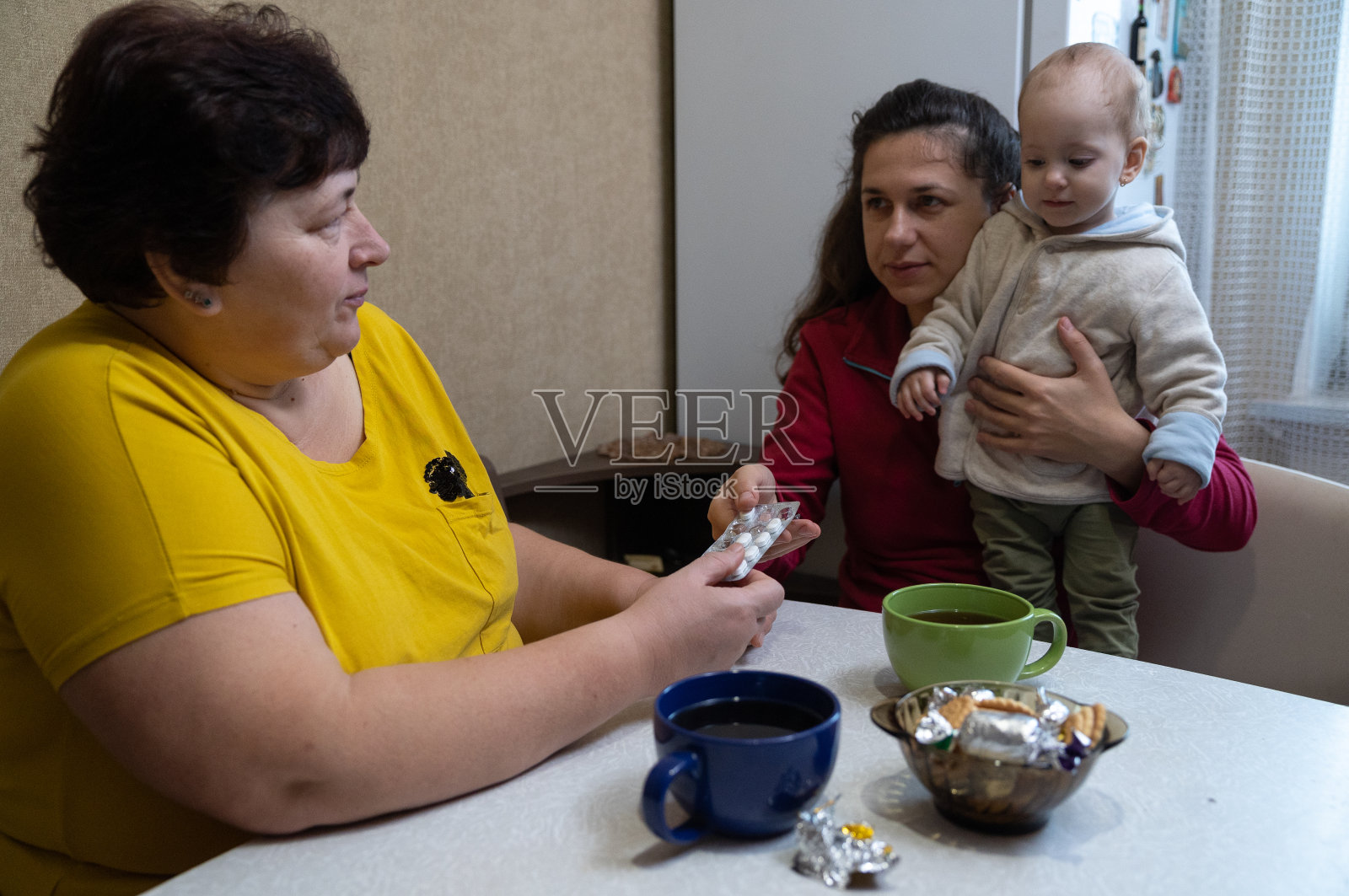 那个女人从她女儿手里拿过药丸。照片摄影图片