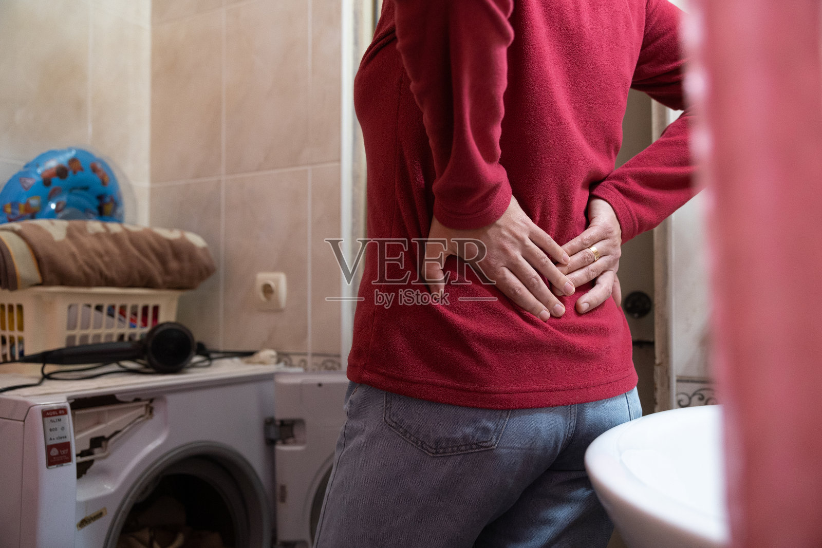 这名妇女在做家务时感到背部疼痛。照片摄影图片