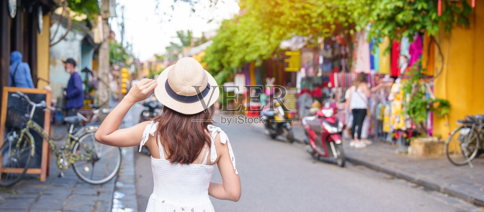 在越南中部的会安古镇观光的快乐旅行者，穿着衣服和帽子的女子旅行。是著名的地标性旅游景点。越南及东南亚旅游概念照片摄影图片