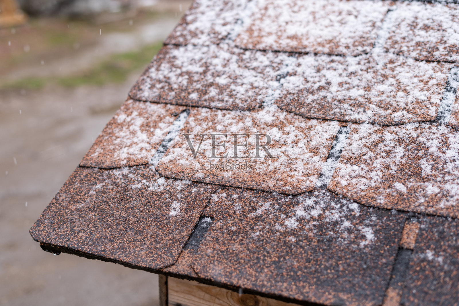 雪落在覆盖着棕色沥青瓦的屋顶上照片摄影图片