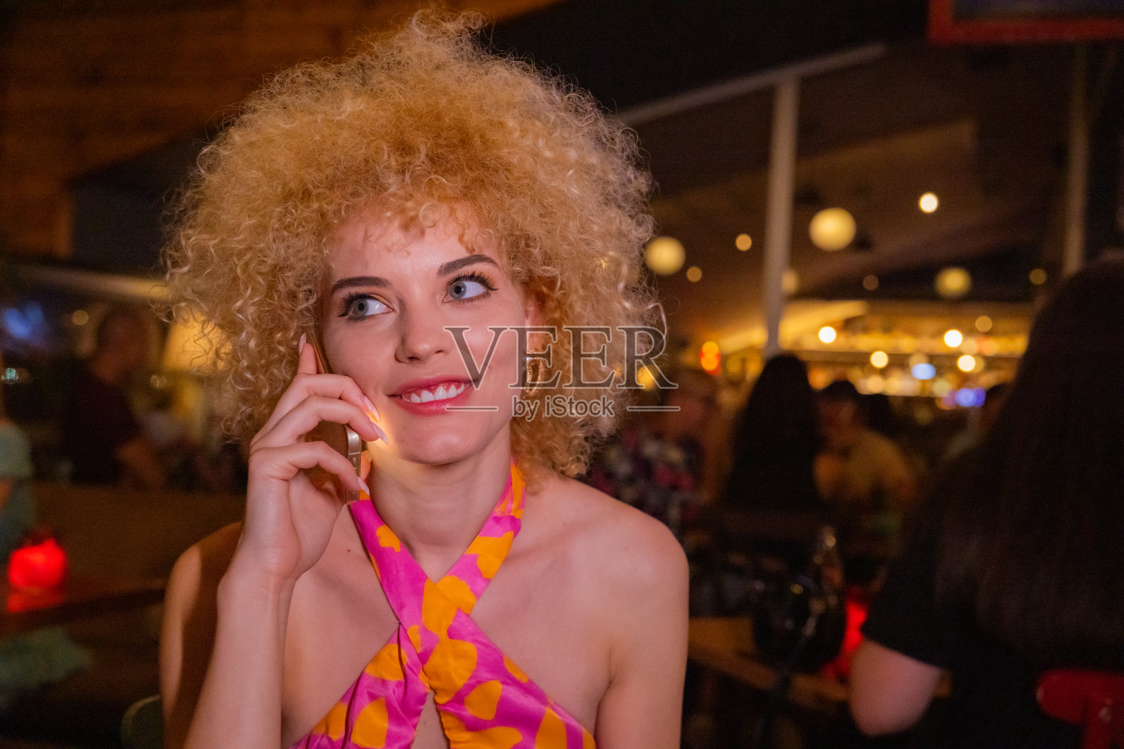 一个金发卷发的城市女人在俱乐部里打电话照片摄影图片