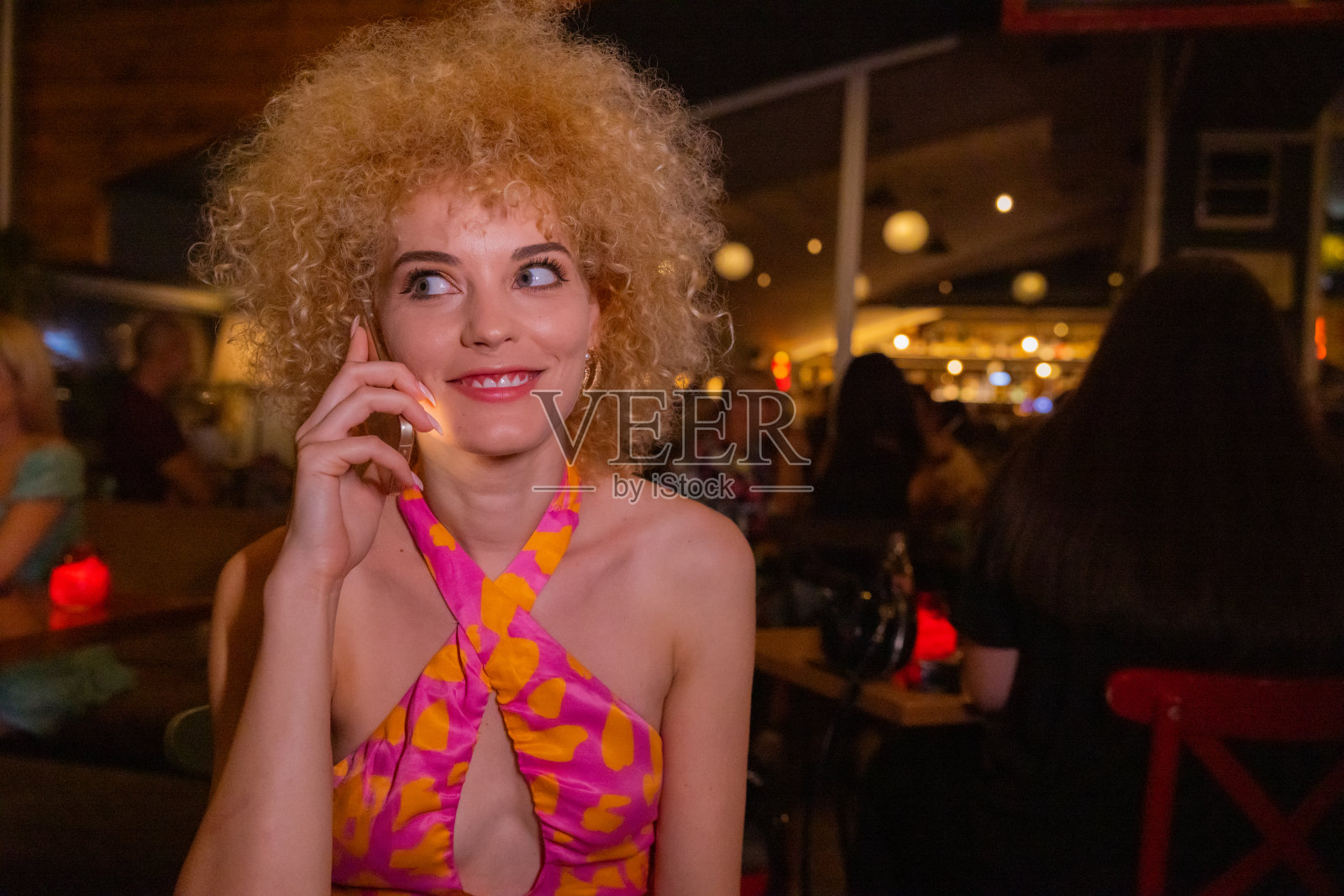 一个金发卷发的女人在俱乐部里打电话照片摄影图片
