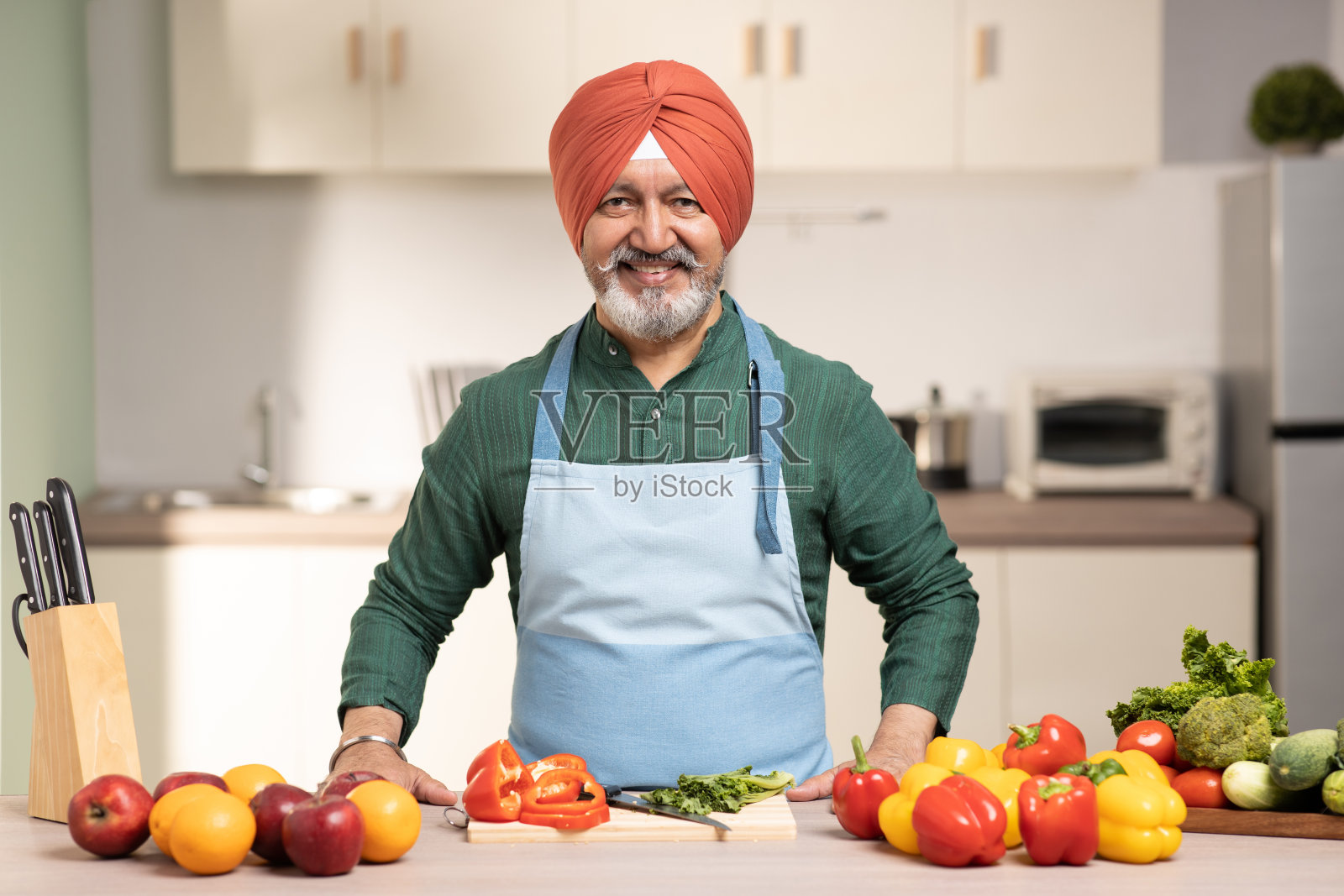 在厨房里戴头巾的成熟锡克教男子，库存照片照片摄影图片