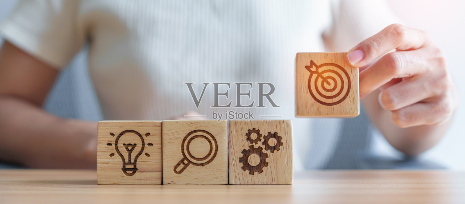 女子手握飞镖上方齿轮，放大和灯泡图标块。商业计划过程，目标，战略，目标，任务，行动，研究，团队合作和理念概念照片摄影图片