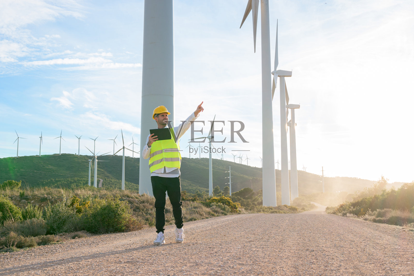 手持平板电脑的工人指着可再生能源风车照片摄影图片