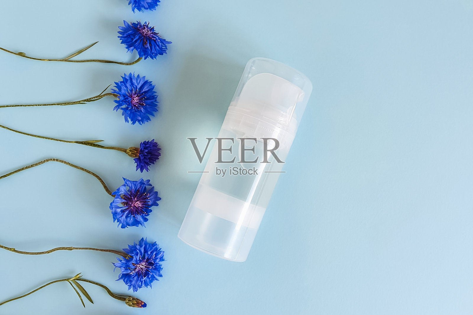 透明瓶亲密的润滑剂凝胶和矢车菊花线边界蓝色背景。贴心按摩，舒适性概念，润滑，润滑。前视图，模型，模板照片摄影图片
