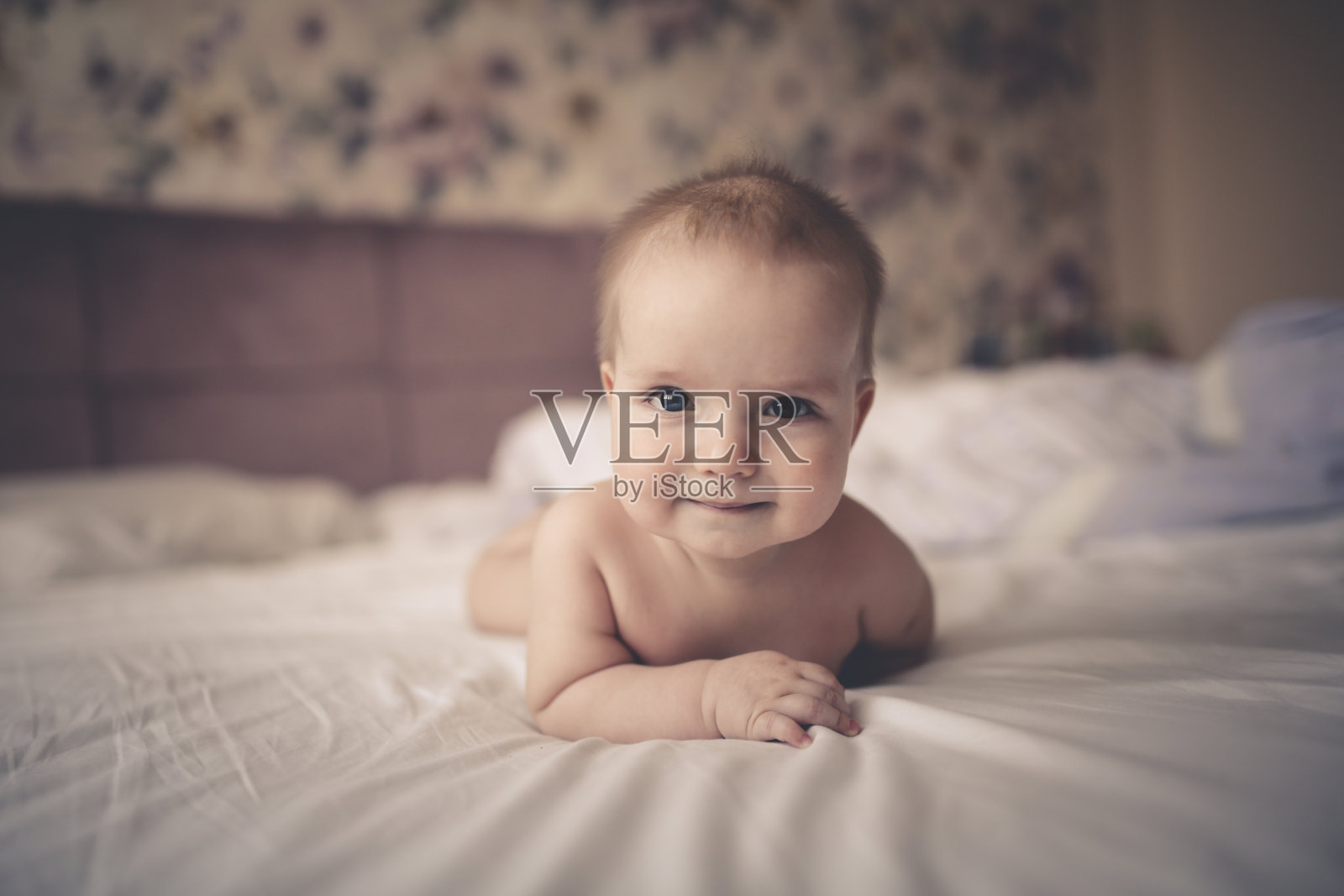 宝宝趴在明亮真实的床上照片摄影图片
