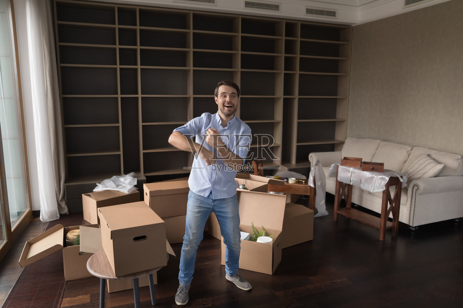 一名男子在满是箱子的客厅跳舞庆祝搬迁照片摄影图片