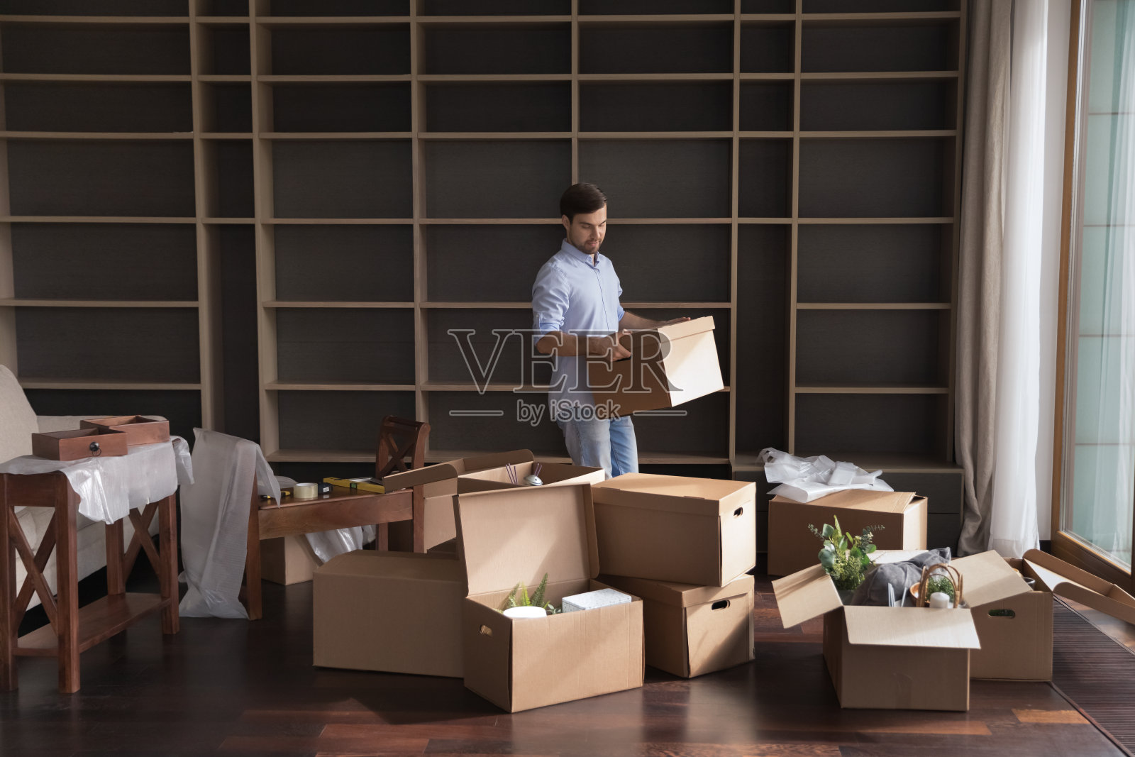 男人把装着东西的纸箱搬到客厅照片摄影图片