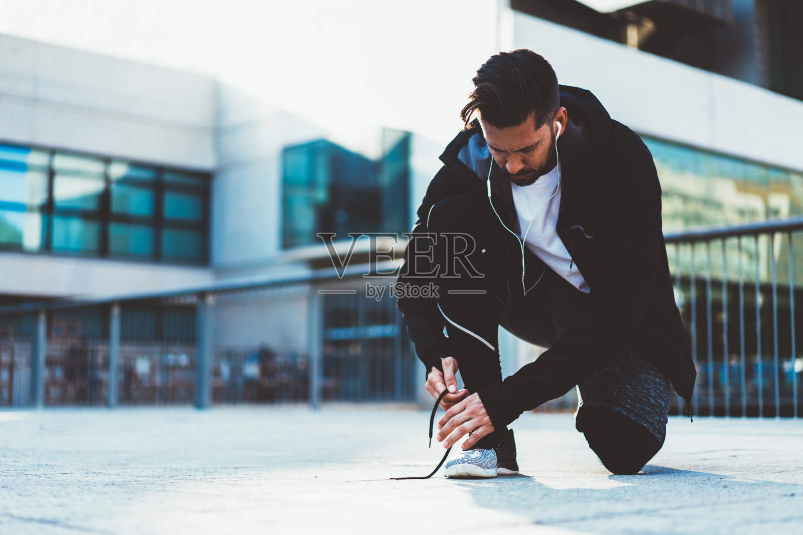 年轻的20多岁男性慢跑者穿着运动服和鞋子准备在街上检查鞋带，男性运动员在慢跑前穿着时尚的跟踪服系运动鞋照片摄影图片