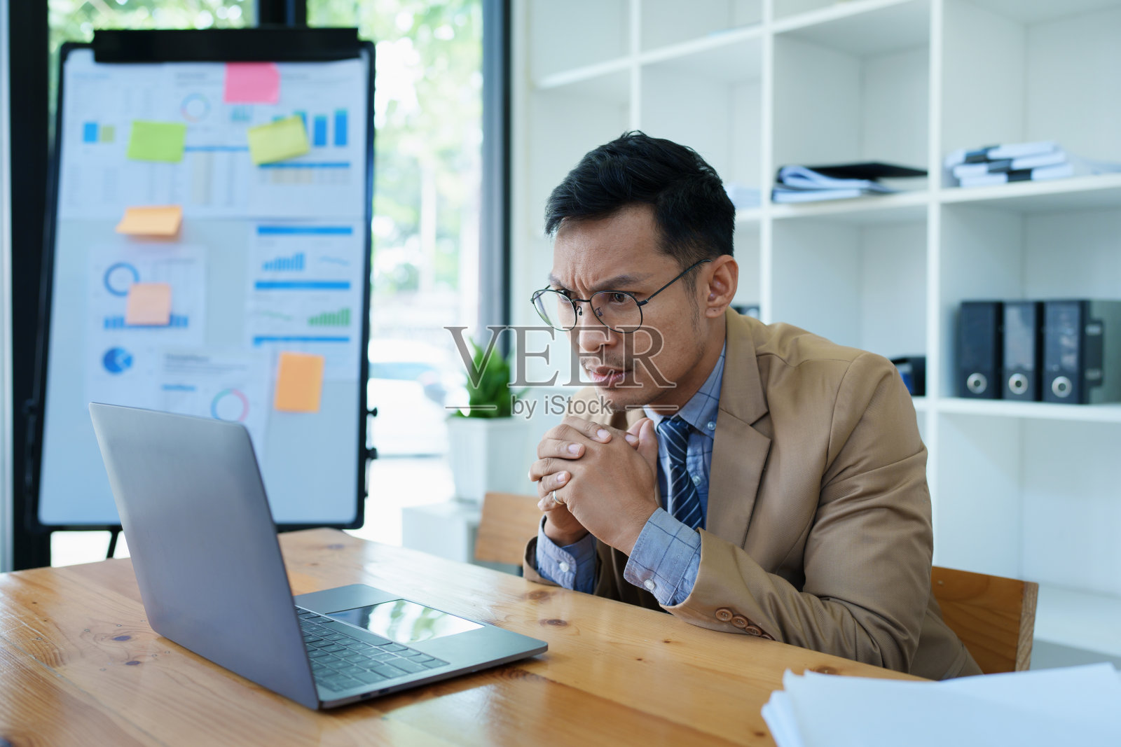 中小企业企业主画像，男子用电脑和财务报表焦虑地表达对扩大市场增加投资能力的企业照片摄影图片