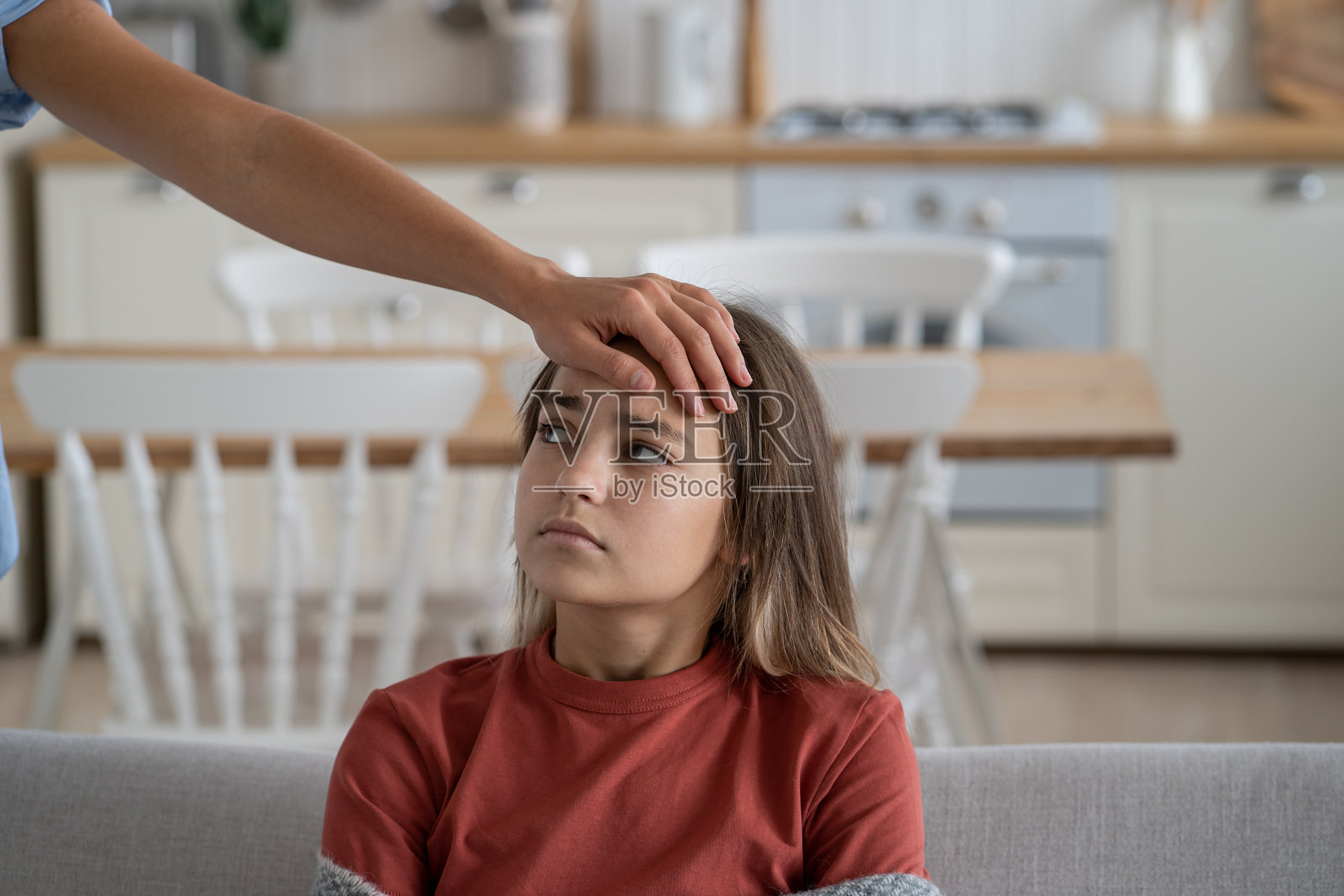 生病的少女，母亲用手测量感染孩子的额头温度照片摄影图片