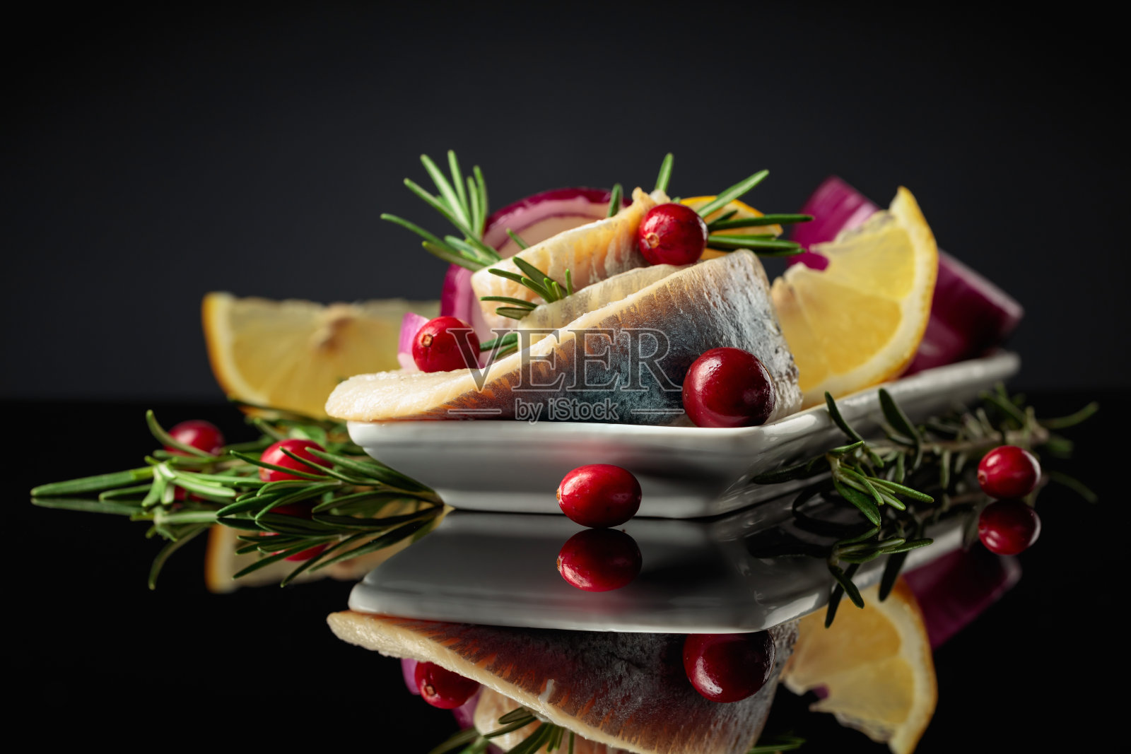 油浸鲱鱼片，柠檬，洋葱，迷迭香和蔓越莓。照片摄影图片